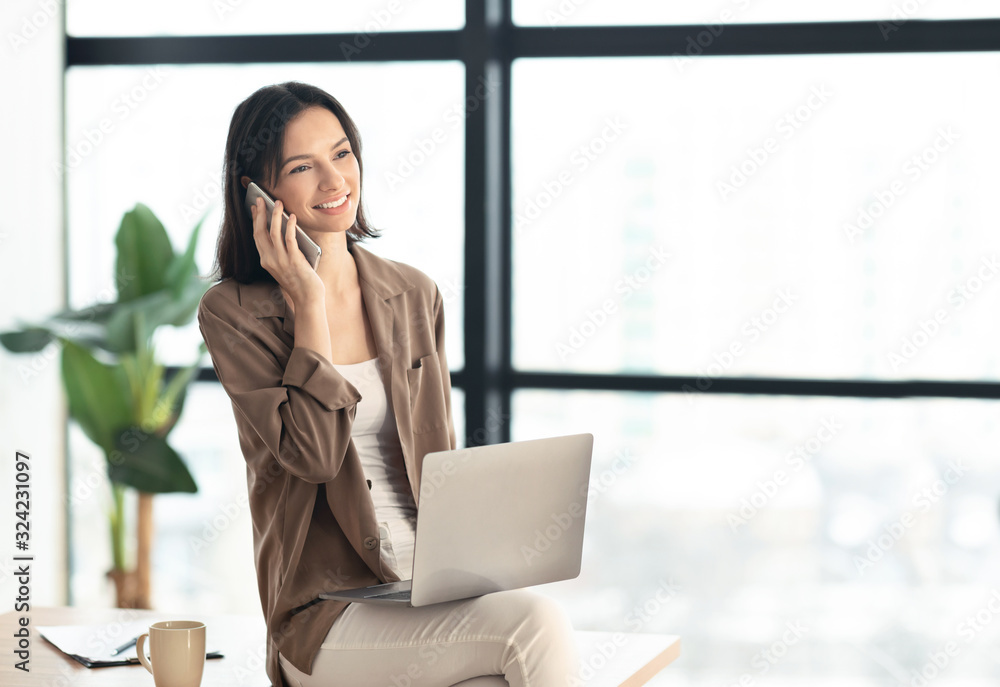 Girl talking on phone sitting on the table looking aside Girl talking on phone sitting on the table looking aside