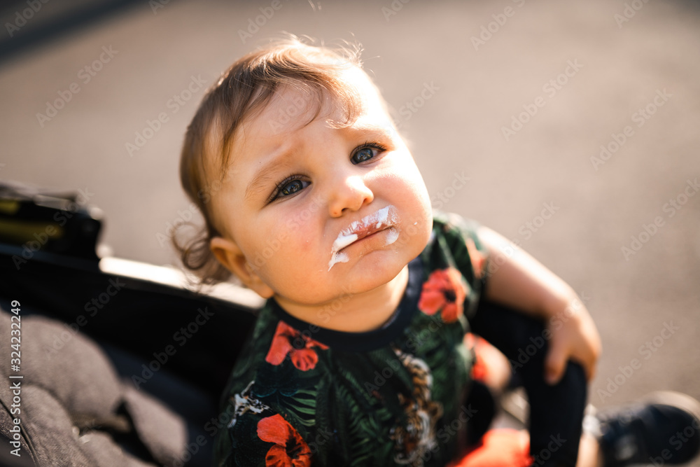 Mother feeding baby child boy ice-cream - Young mom and her baby eat white vanilla creamy dessert - Sits in a baby carriage pram - Caucasian family 1 year old Mother feeding baby child boy ice-cream - Young mom and her baby eat white vanilla creamy dessert - Sits in a baby carriage pram - Caucasian family 1 year old