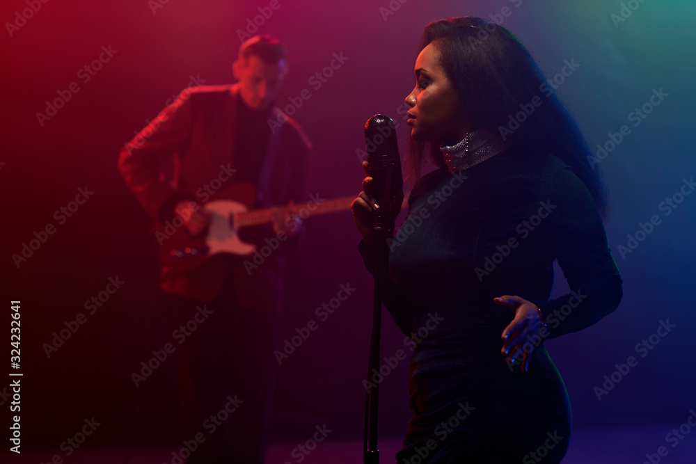 Obraz premium A jazz singer and guitarist perform on stage.