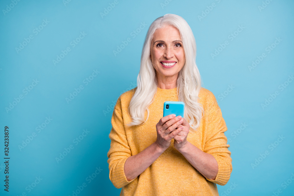 Close-up portrait of her she nice attractive lovely cheerful cheery grey-haired woman using modern device writing sms message isolated over bright vivid shine vibrant blue color background Close-up portrait of her she nice attractive lovely cheerful cheery grey-haired woman using modern device writing sms message isolated over bright vivid shine vibrant blue color background