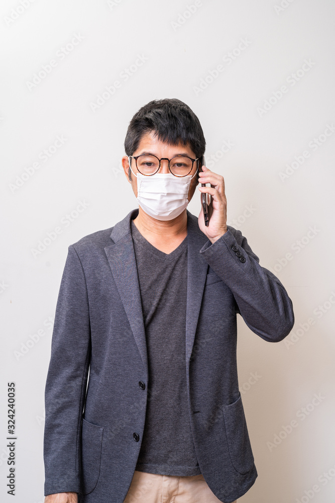 Asian man wearing surgical mask to prevent flu disease Coronavirus and using smartphone