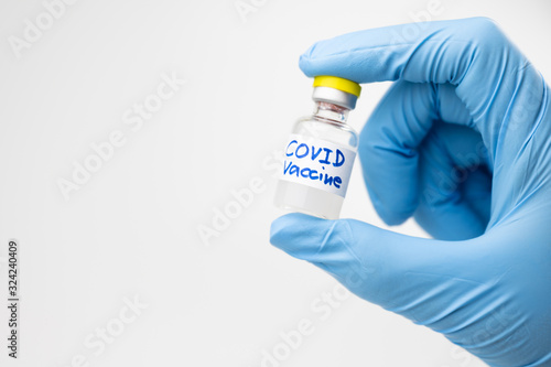 Doctor, nurse or scientist hand holding coronavirus lab tube, covid-19 vaccine