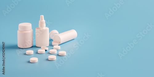 three white plastic medicine bottles for pills without labels and scattered tablets