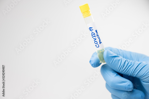 Doctor, nurse or scientist hand holding coronavirus lab tube, covid-19 vaccine