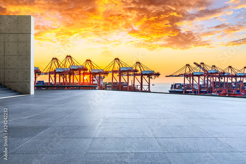 Empty square floor and industrial container terminal at beautiful sunset in Shanghai.