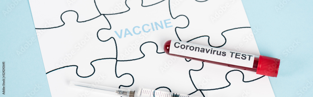 panoramic shot of puzzle pieces with vaccine lettering near sample with coronavirus test and syringe on blue panoramic shot of puzzle pieces with vaccine lettering near sample with coronavirus test and syringe on blue