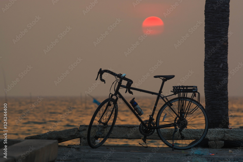 A bicycle with a sea backdrop at sunset