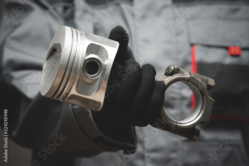Tableau sur toile Old car engine piston on connecting rod in auto mechanic hand close up