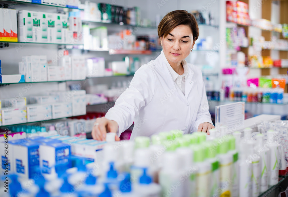 Fotografie Female pharmacist arranging displayed assortment