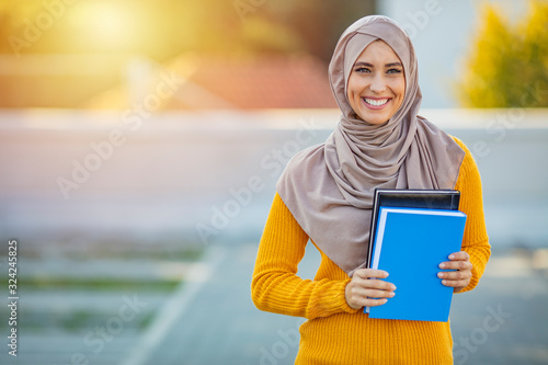 Canvas Print Muslim girl, a college student, holding her workbooks at student campus