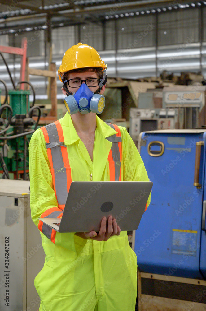 Caucasian male with protective mask with laptop working in factory area. Caucasian male with protective mask with laptop working in factory area.