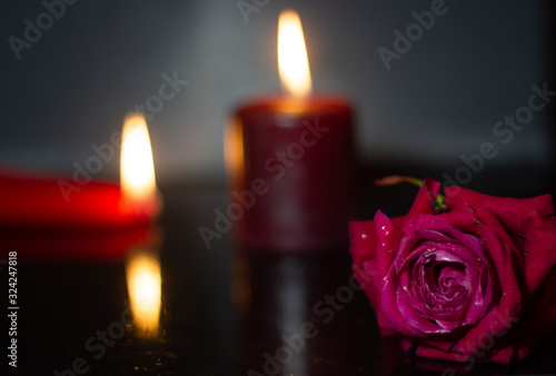 one rose is red close against the background of red candles