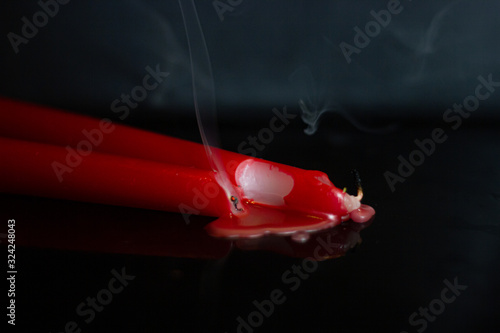 red candles burn on the table in the dark and reflect the flames photo