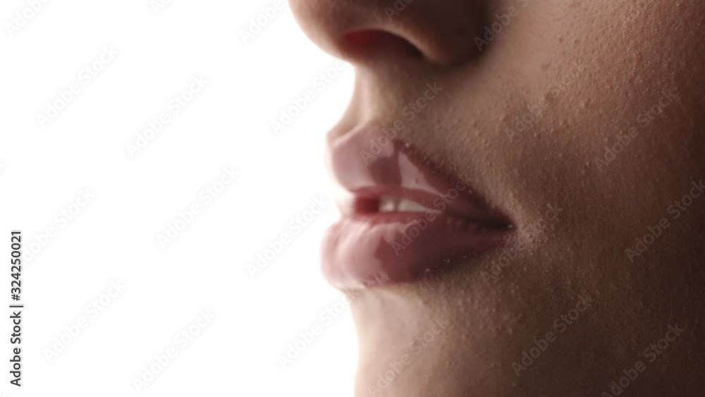 The girl sexually licks her lips with her tongue. Close up on a white isolated background. Shiny wet lips. The girl sexually licks her lips with her tongue. Close up on a white isolated background. Shiny wet lips.