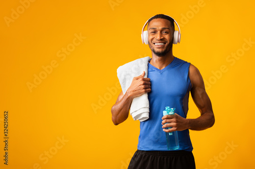 Fototapeta Naklejka Na Ścianę i Meble -  Healthy afro sports guy holding bottle of mineral water