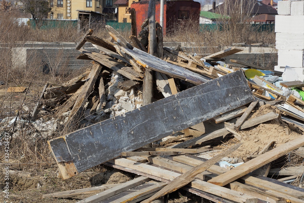 Fototapeta premium gray and brown wooden boards in a heap of garbage outdoors on a sunny day