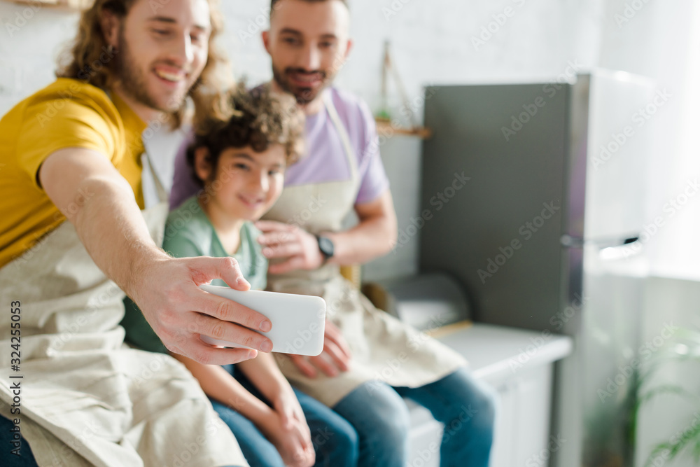 selective focus of happy homosexual men taking selfie with cute mixed race son selective focus of happy homosexual men taking selfie with cute mixed race son