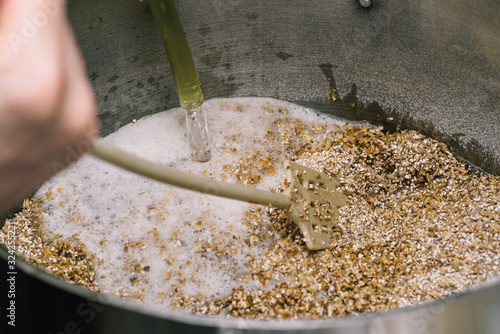 Stirring the malt with a long stirrer. Water is sprayed into the malt tank. The technology of making beer.
