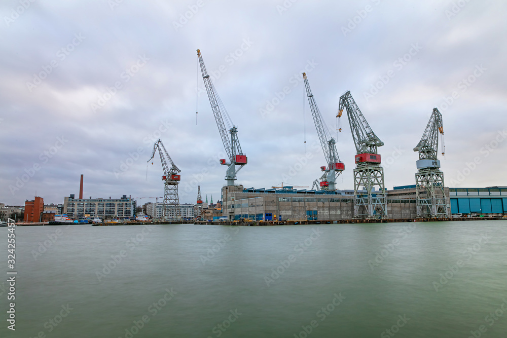 City working area, cargo port with cranes on the seashore. Helsinki panorama, Finland - February 18, 2020: Lautasaari island in cloudy weather. Early morning.