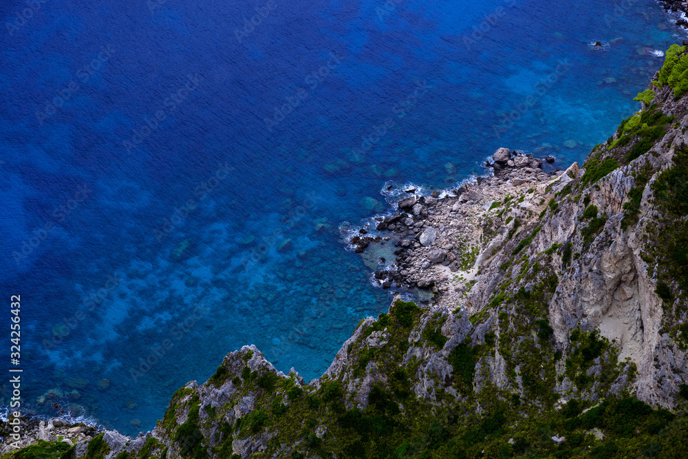 Aerial view of sea and rocky coast on sunny day.