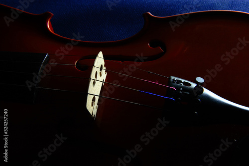 Detalle de violín con enfoque selectivo y fondo oscuro en clave baja. photo