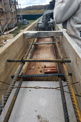 Worker lines concrete in formwork with trowel, construction of new home.