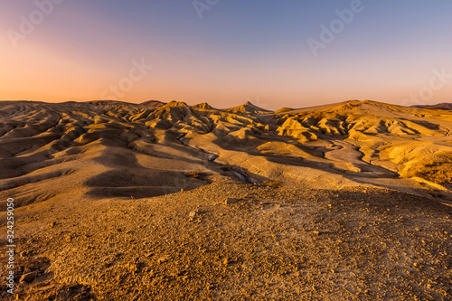 Beautiful lunar landscape with golden light at sunset over the muddy volcanoes, Paclele, Berca, Buzau County, Romania