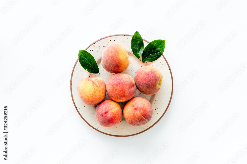 Summer fruits. Ripe red peaches on plate on white table top-down copy space Summer fruits. Ripe red peaches on plate on white table top-down copy space