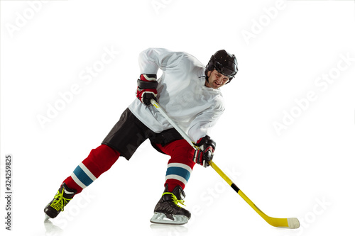 Obraz na płótnie Attented. Young male hockey player with the stick on ice court and white background. Sportsman wearing equipment and helmet practicing. Concept of sport, healthy lifestyle, motion, movement, action. w salonie