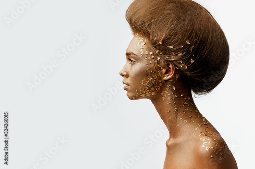 Fototapeta Moda sztuka portret model dziewczyna z wakacje złoty błyszczący profesjonalny makijaż. kobieta ze złotym metalicznym ciałem i włosami na białym tle. Złota świecąca skóra. kopiuj przestrzeń