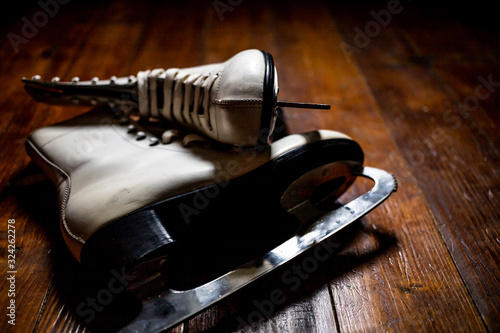 Old, white ice skates on the wooden floor. Winter sports