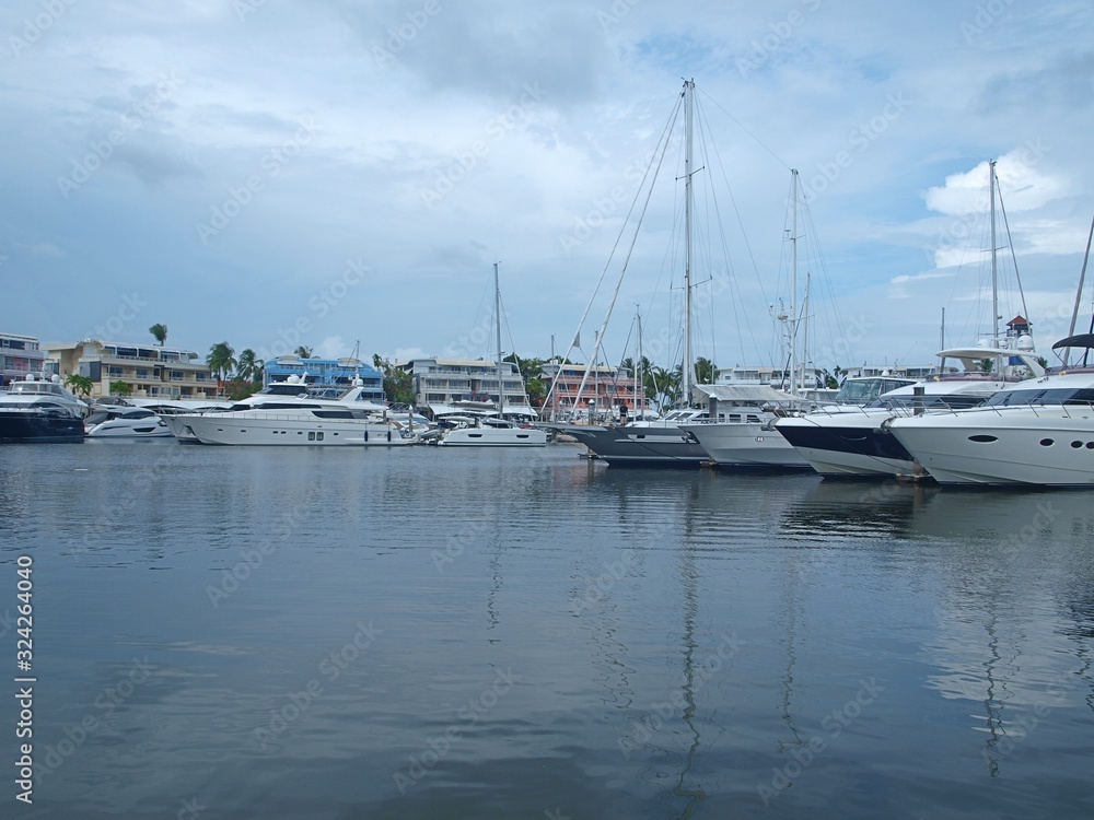 Panoramic view of beautiful clouds, blue sky and calm sea water, stunning yachts located in the yachts club, buildings and hotels. Panorama of coastal luxury resort. 