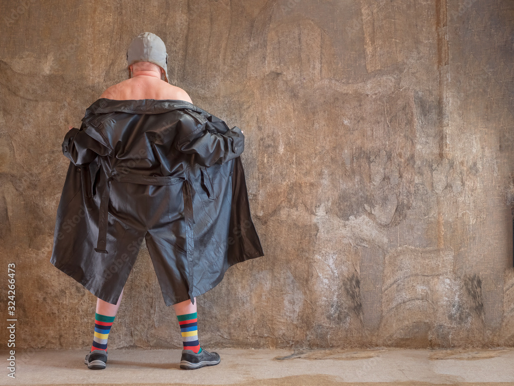 Fototapeta premium elderly man in pink pajamas, rabbit ears and leather coat of exhibition maniac is dancing against background of imitating mold. concept of perversions of bizarre people. Gray beard and wrinkled face