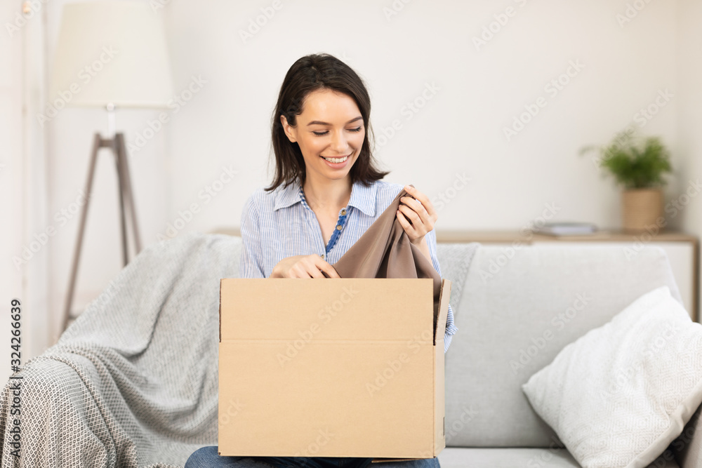 Smiling girl putting clothes in cardboard box Smiling girl putting clothes in cardboard box