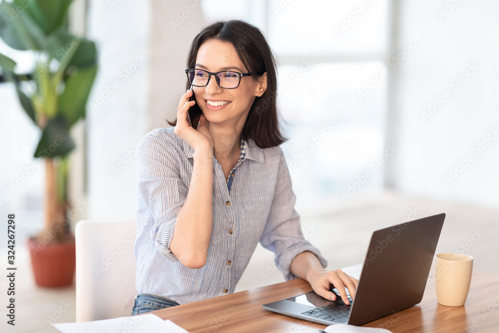 Smiling young businesswoman talking on her cell phone Smiling young businesswoman talking on her cell phone
