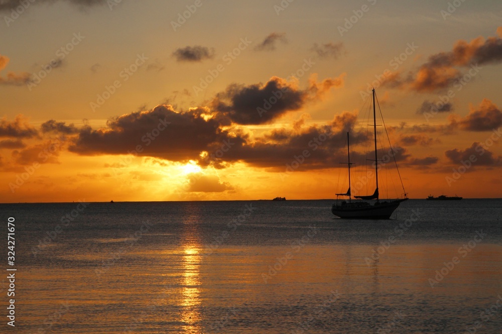 Silhouette of a sailboat moored in the lagoon with a golden sunset