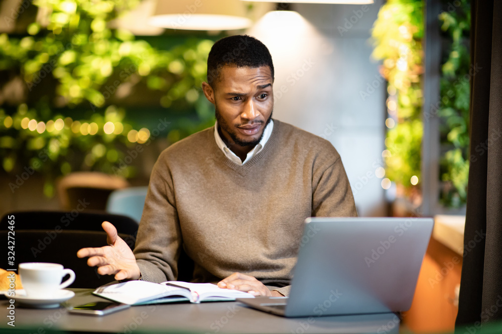 Fotografie Surprised young black manager looking at his computer