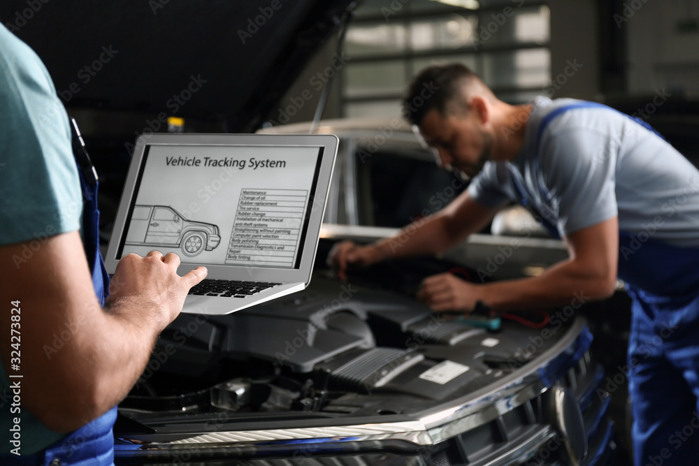 Mechanic with laptop doing car diagnostic at automobile repair shop, closeup Mechanic with laptop doing car diagnostic at automobile repair shop, closeup