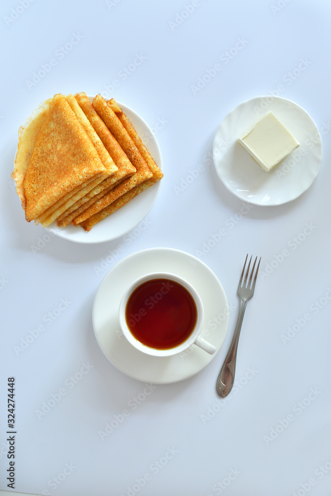 Pancake week: thin pancakes with butter and tea on white table.french crepes .thin pancakes and glass of milk on the table.Delicious breakfast.Selective focus Pancake week: thin pancakes with butter and tea on white table.french crepes .thin pancakes and glass of milk on the table.Delicious breakfast.Selective focus