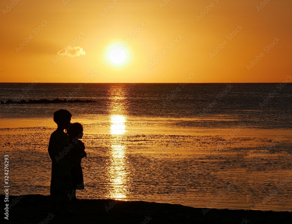 Silhouette of two chilcdren standing and admiring a beautiful sunset