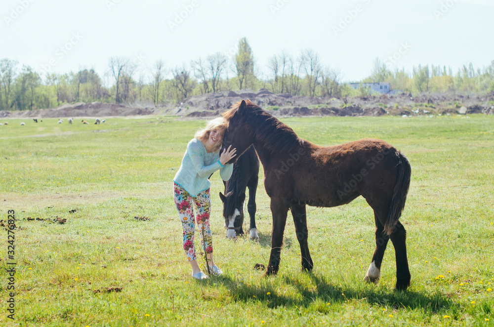 . Spring, trees are blooming, grass is growing . .woman walks on a background of a horse. .woman stroking a horse