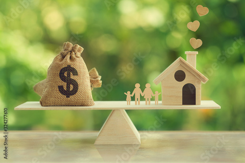 Property investment and house mortgage concept : Wooden home, Family member  and US dollar hessian bags on wooden balance scale. depicts family financial management for a residence. photo