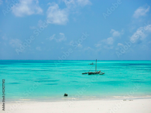 Wooden African boat in the beautiful azure waters of the ocean near the coast of a tropical island with white sand