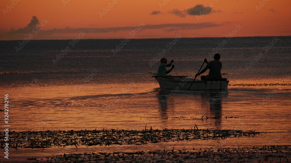 Silhouette of two boaters in the sea at sunset