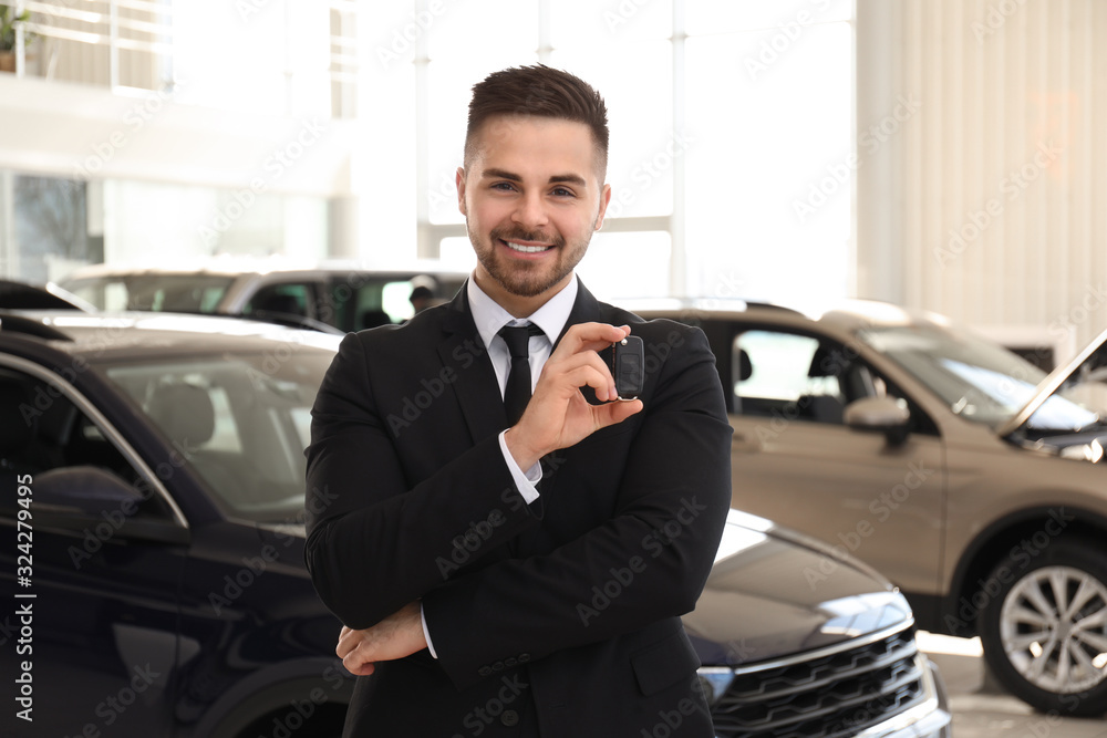 Salesman with key in modern car salon Salesman with key in modern car salon