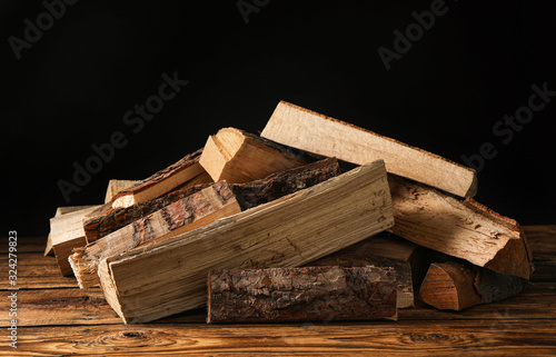 Cut firewood on table against black background