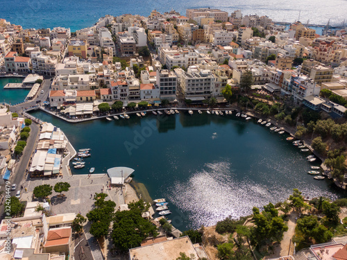 Lake Voulismeni in Agios Nikolaos on Crete island in Greece, in frame the boats and city streets, houses of local residents, aerial photography