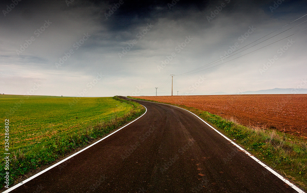 Carretera atravesando campos de cultivo a los lados de dos colores