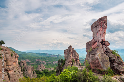 Landscape with bizarre rock formations, green mountain valley and cloudy sky in the background, Belogradchik Rocks is one of the most impressive rock formations in Europe, Balkans Mountain, Bulgaria. photo