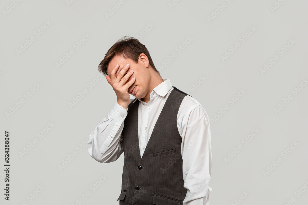 Handsome man in a white shirt and grey vest clutches head because he faces some problems. Handsome man in a white shirt and grey vest clutches head because he faces some problems.